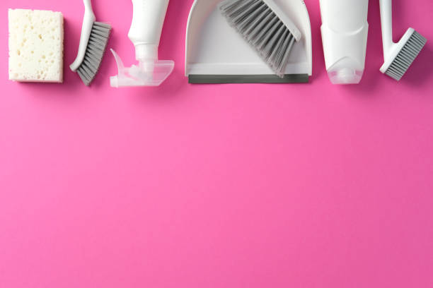 istock Cleaning supplies on a pink background, including sponge, scrub brushes, spray bottle, dustpan, and brush. Ideal for cleaning product ads or articles 2200116493