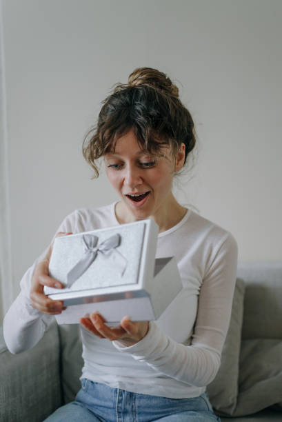 istock Surprised young woman opening a gift box at home 2200116884