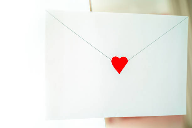 craft envelope made of white paper with a small cute heart. the envelope is located on the background of the interior. horizontal photo