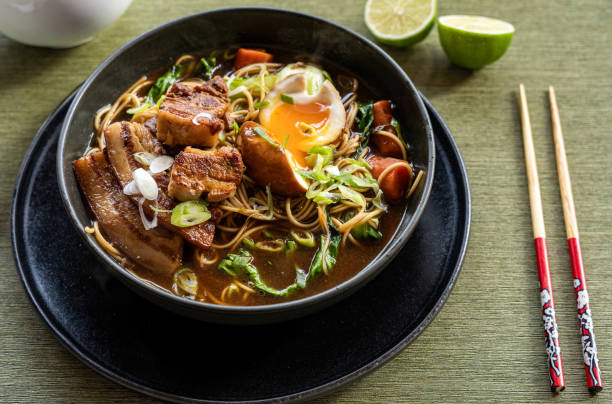 istock Steaming ramen bowl featuring tender chashu pork, soft egg, rich broth, springtime onions, colorful vegetable medley 2200124403