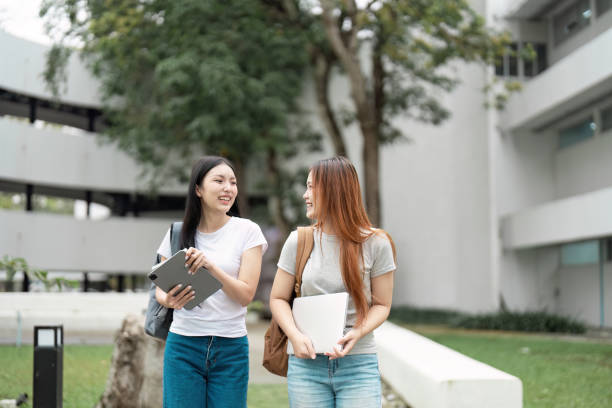istock Two cheerful students walking on campus, carrying laptops and enjoying a friendly conversation in a vibrant outdoor setting 2200124831