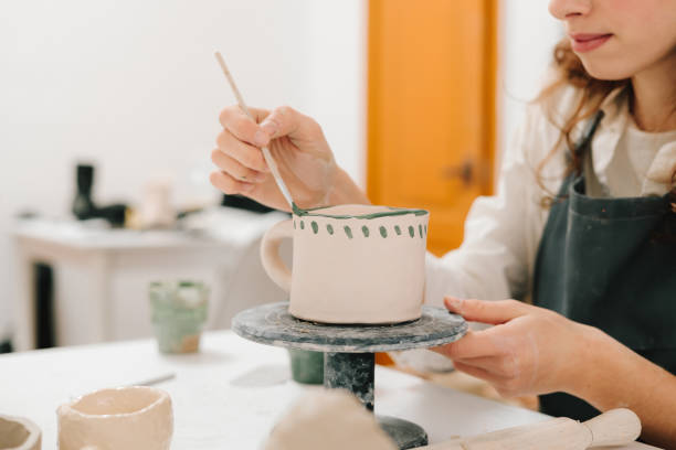 istock Painter is drawing and adding unique designs to the earthenware. Artist is decorating and painting handmade ceramic clay cup in the creative workshop. 2200125386