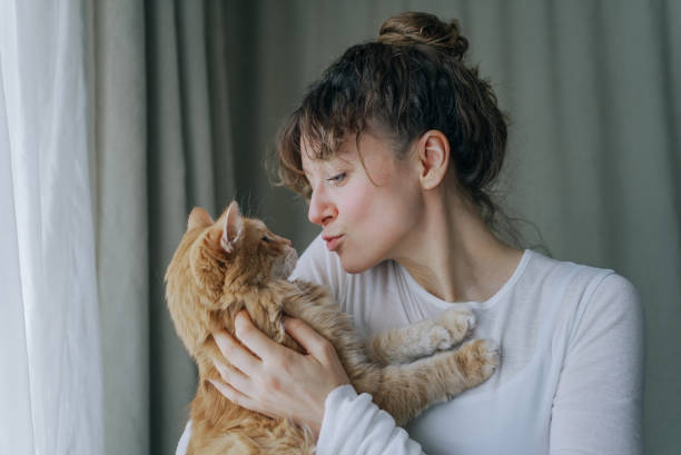 istock Woman showing affection to ginger cat by kissing it 2200125515