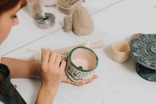 istock Design earthenware cup with a traditional pattern. Artist is making decoration on the clay ceramic mug after oven firing. 2200125832