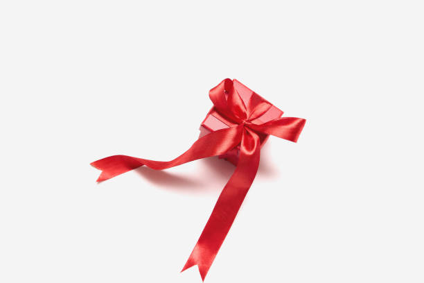 A small red gift box adorned with a shiny ribbon sits on a plain white background, suggesting anticipation for a special celebration.