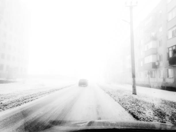 Buildings and power lines fade into the fog, creating an eerie yet peaceful atmosphere. The journey ahead is uncertain, yet strangely inviting.
