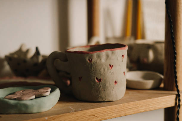 istock Shelf with handmade clay cups and plates in the pottery studio. Creating ceramics ware with own hands. 2200126094