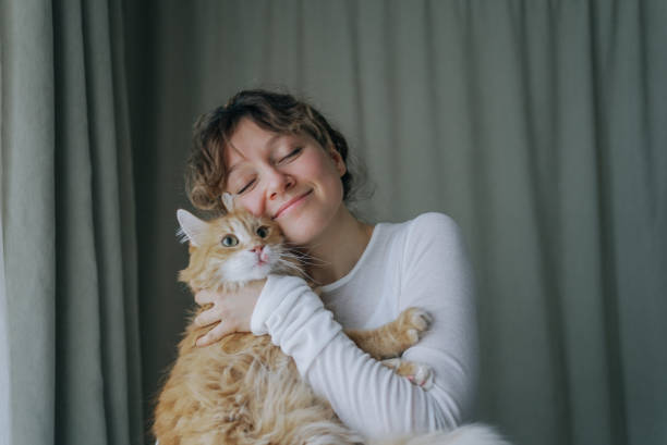 istock Woman gently hugging her ginger cat with closed eyes and smiling 2200126133
