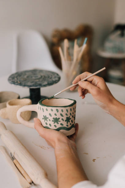 istock Design earthenware cup with a traditional pattern. Artist is making decoration on the clay ceramic mug after oven firing. 2200126176