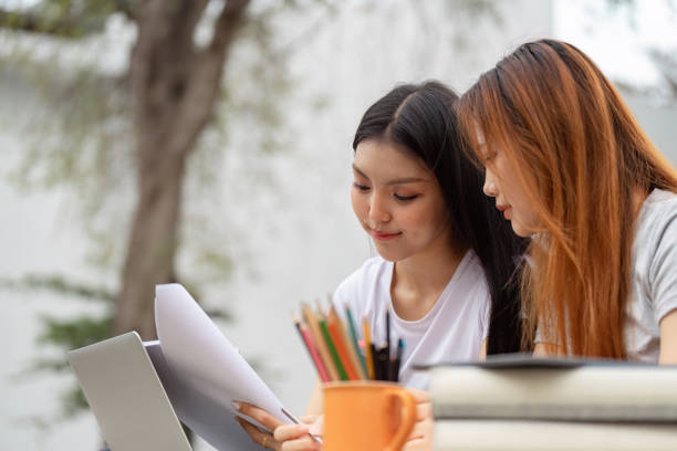 istock Diverse female students focused on study materials with laptop and stationery. 2200126294