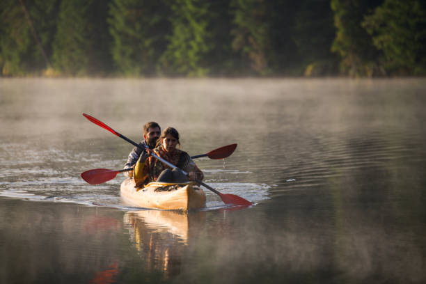 istock Exploring nature together: couple kayaking on a misty lake. 2200126910