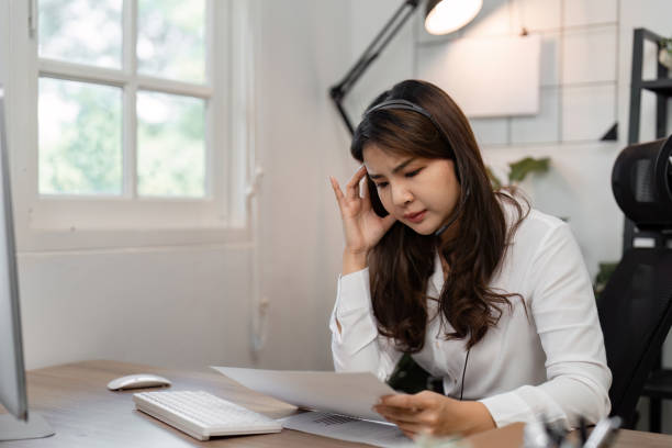 istock Concerned Asian female call center agent reviewing customer feedback documents at a modern workspace, reflecting on service challenges. 2200127440
