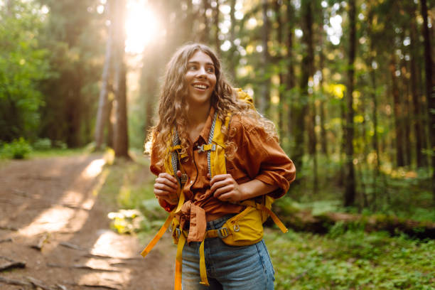 istock Young woman carrying backpack while walking among trees in the forest. 2200128577