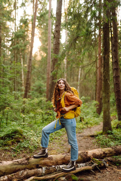 istock Young woman carrying backpack while walking among trees in the forest. 2200128586