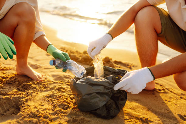 istock Volunteers with polyethylene bag picking up a plastic bottles on the beach. 2200129937