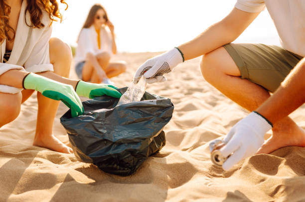 istock Volunteers with polyethylene bag picking up a plastic bottles on the beach. 2200129939