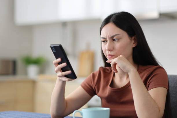 Suspicious asian woman checking phone in the kitchen Suspicious asian woman checking phone content in the kitchen at home suspicious message stock pictures, royalty-free photos & images
