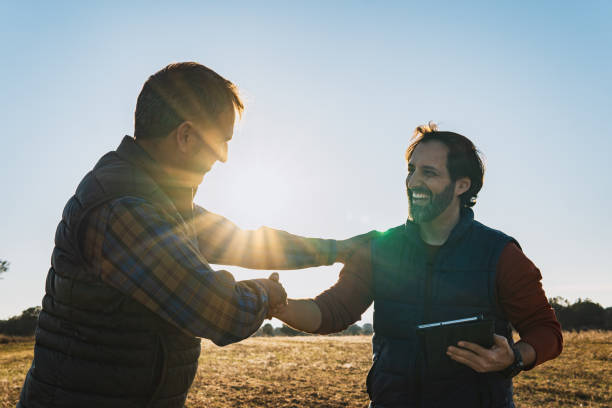 Two men closing an agricultural agreement with a handshake in the field.