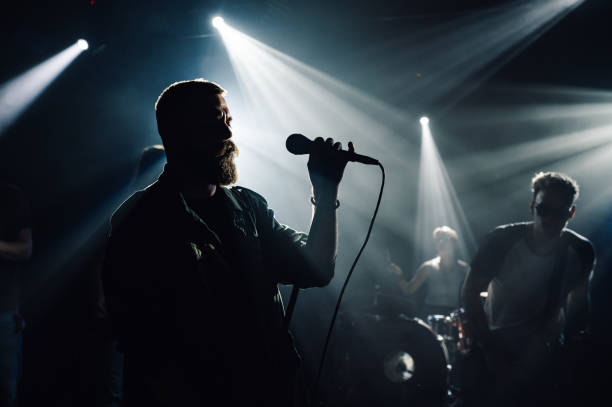 istock Singer performing with band on dark stage with spotlights 2200132463