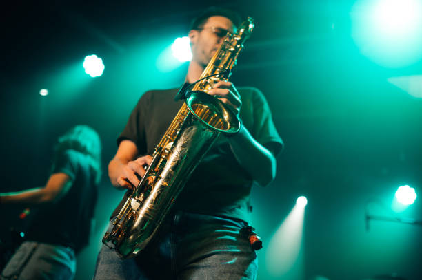 istock Saxophonist performing live on stage with teal lighting 2200132556