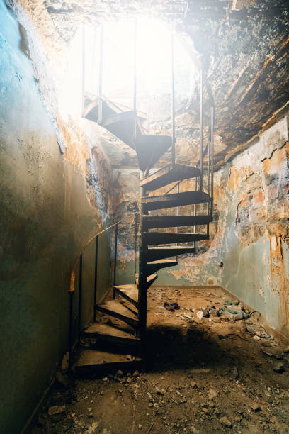 istock Rusty spiral staircase in abandoned building leading to bright light above, surrounded by crumbling walls and debris. Atmosphere of decay, mystery, and forgotten past 2200132660