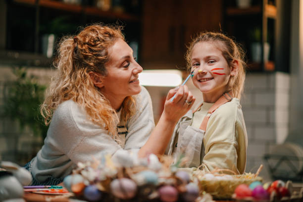 istock Mother painting daughter's face for easter celebration at home 2200132958