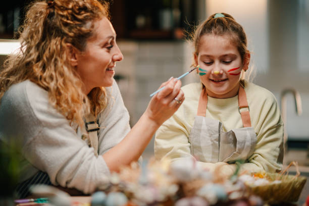istock Mother painting daughter's face for easter celebration at home 2200132964