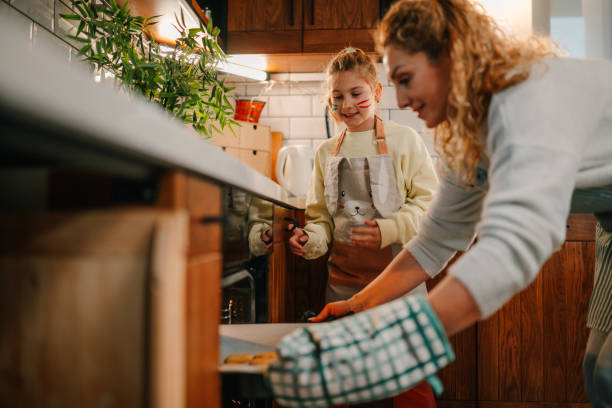 istock Mother and daughter baking cookies together in modern kitchen 2200132978