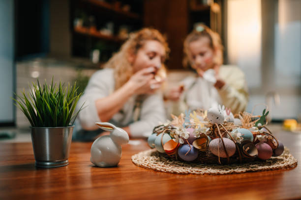 Easter wreath with colorful eggs and ceramic bunny decorating a wooden table