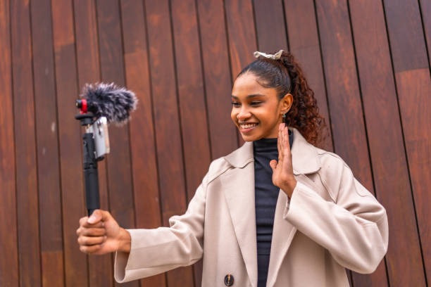 istock Influencer waving at camera while recording vlog outdoors 2200136008