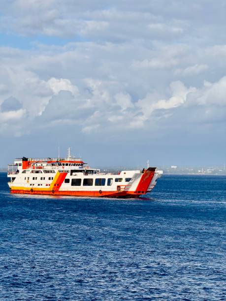 istock Large ferry sailing across the Bali Strait under a cloudy sky with deep blue ocean water. Passenger and vehicle transport ferry connecting Bali and Java, Indonesia, with an open ramp and vibrant colors. 2200136545