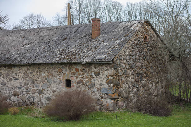 istock .an old stone building with two chimneys and small windows, situated in a wooded area. 2200136808