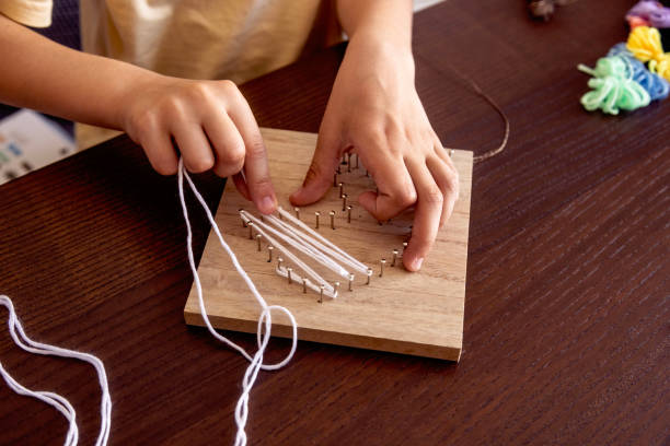 istock Little hands weave string around nails, crafting a beautiful design. A mix of patience, learning, and fun 2200142932