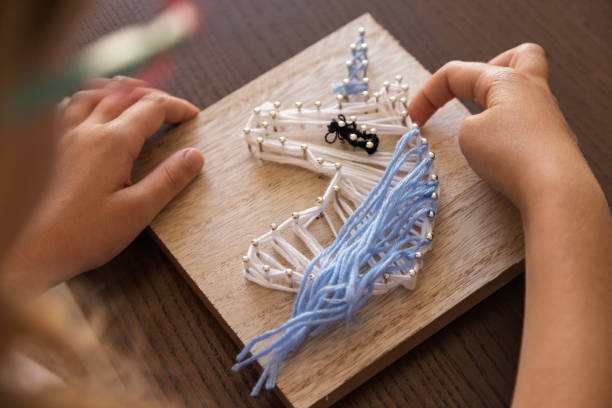 istock Child creates intricate string art. Fostering focus, creativity, patience, and therapeutic skill development. 2200143045