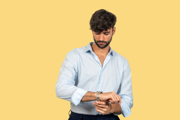 istock Businessman checking time on wristwatch on yellow background 2200145644