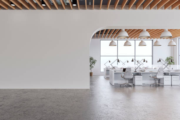 istock Semi-empty office interior with arched white blank wall and copy space,  a wooden slats ceiling, work desks and large windows, on cement floor 2200147901