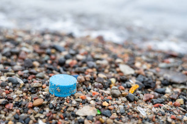 istock Plastic bottle cap on sea beach with waves behind, ocean plastic pollution 2200148065
