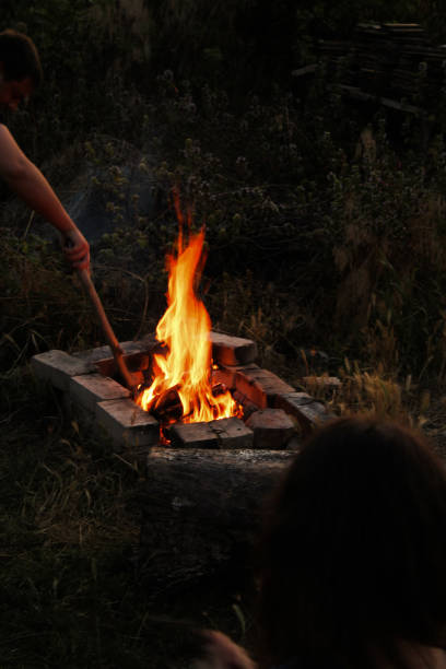istock A man is stirring a large fire using a long wooden stick carefully 2200148141
