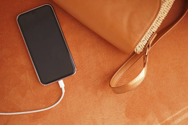 istock A modern smartphone is conveniently being charged next to a stylish handbag on a soft surface 2200148901