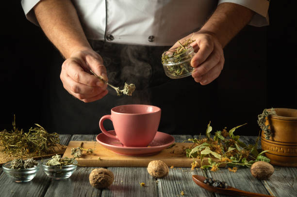 istock Hands skillfully add aromatic herbs to a warming cup, releasing steam as the comforting atmosphere fills the kitchen with earthy scents. Nature's bounty comes alive in this mindful tea preparation 2200149908