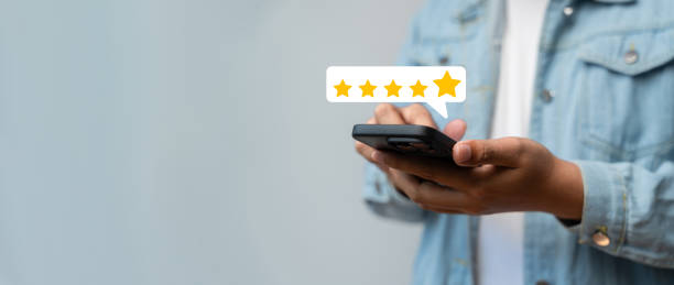istock Close-up man using a smartphone to provide a five-star service rating, Customer satisfaction survey and feedback, Online reviews, Service quality evaluation, Customer service experience. 2200155092
