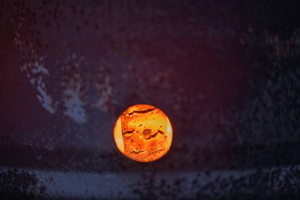 A fiery core glows through a circular opening in a dark, weathered surface—suggesting intense heat within a furnace or incinerator. The glowing textures and rich colors evoke themes of energy, transformation, metallurgy, or power generation. Ideal for conceptual, industrial, or symbolic imagery.