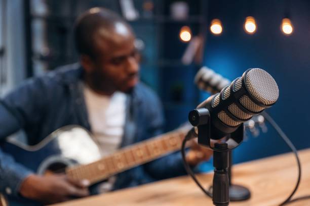 istock Playing acoustic guitar. Man is doing podcast in the studio 2200155857