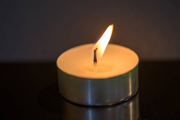 istock Lit Tealight Candle on Dark Surface — Calm, Reflection, and Mindfulness Concept 2200156438