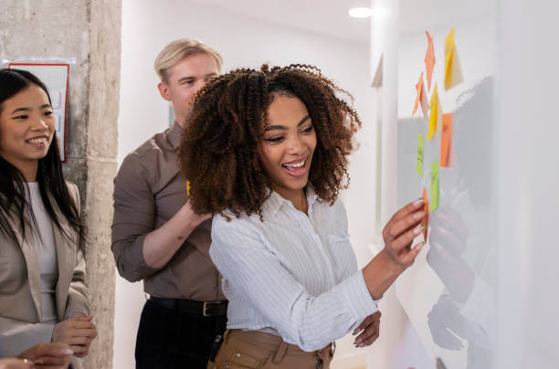 istock Businesswoman placing sticky notes on whiteboard during brainstorming session 2200157586