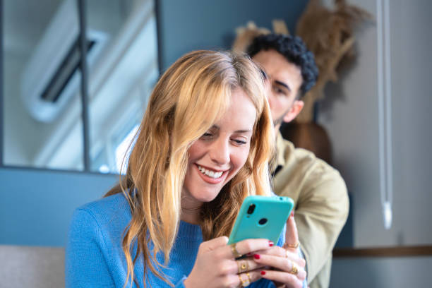 istock Smiling Woman Using Smartphone with Friend in Background 2200157652