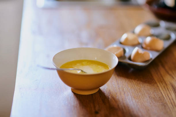 Table, bowl or whisked eggs with shells for protein, baking or preparing breakfast for meal or snack at home. Closeup, mixed or yolk with poultry dish or ingredients for morning, nutrition or vitamin
