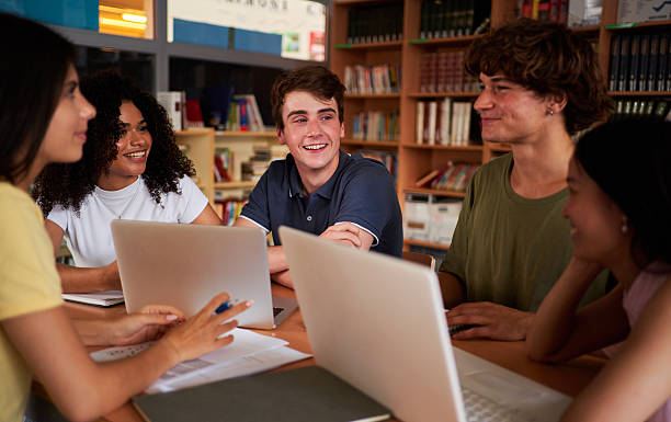 istock Group of students gathered in the library to work together on a school project, using laptops. 2200160283