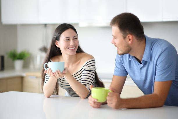 istock Interracial couple talking and drinking in a kitchen 2200160320