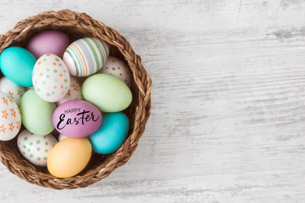 istock Easter Eggs in a Basket on White Wooden Background 2200160368